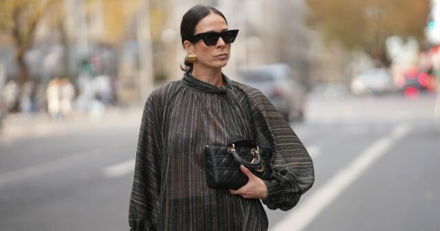 Amanda Mühle é vista vestindo um casaco de lã cinza com lapelas largas, fecho de botão e gola abotoada da Siyazu; um suéter de malha estampado em tom suave de verde e rosa com padrão argyle e textura de mistura de lã macia da Marc O'Polo Denim; uma camiseta branca de algodão da COS usada por baixo; jeans azul com corte reto e solto da Zara; botas Mou de camurça bege com sola plataforma e detalhes costurados exclusivos da Mou; uma “bolsa City” Balenciaga de couro rosa com formato suavemente desleixado, alças superiores e detalhes prateados da Balenciaga; vários anéis de prata da Pilgrim; segurando uma revista Vogue; óculos estilo aviador com armação rosa e lentes levemente coloridas da Lexxola; brincos de prata com acabamento escultural da Mango; seus longos cabelos castanhos estão soltos e repartidos de lado em 8 de janeiro de 2026 em Munique, Alemanha.