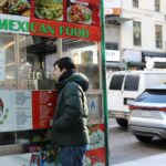 Uma mulher troca uma bateria em um carrinho de comida em uma rua da cidade.