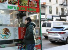 Como o PopWheels ajudou um carrinho de comida a substituir geradores por baterias de bicicletas elétricas Uma mulher troca uma bateria em um carrinho de comida em uma rua da cidade.
