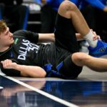 O atacante do Dallas Mavericks, Cooper Flagg (32), agarra o tornozelo ao cair no chão durante o segundo quarto contra o Denver Nuggets, no American Airlines Center.