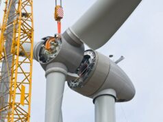 Desenvolvedores eólicos offshore processam a administração Trump por interromper US$ 25 bilhões em projetos A crane positions the rotor of a wind turbine during construction.
