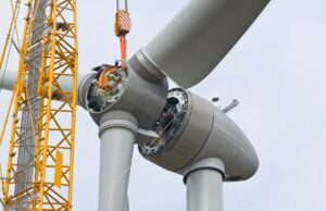 Desenvolvedores eólicos offshore processam a administração Trump por interromper US$ 25 bilhões em projetos A crane positions the rotor of a wind turbine during construction.
