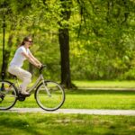 A woman cycling through a park.