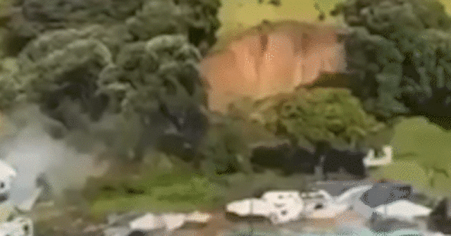 Nesta imagem de um vídeo, um policial com um cachorro revista pessoas perto do local de um deslizamento de terra na base do Monte Maunganui, na Ilha Norte da Nova Zelândia, quinta-feira, 22 de janeiro de 2026. 