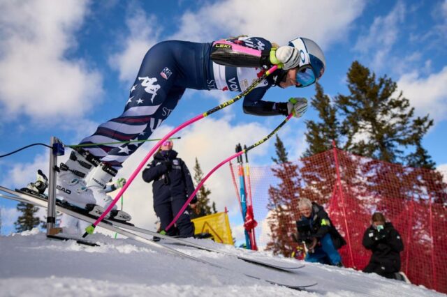 A esquiadora Lauren Macuga, à esquerda, olha para seu celular com o técnico de esqui Rok Javor e a esquiadora Jackie Wiles enquanto eles pegam o teleférico colina acima para o treino da equipe feminina de esqui dos EUA em Copper Mountain, Colorado, 19 de novembro de 2025. (AP Photo/Jacquelyn Martin)