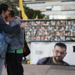 Duas mulheres abraçam-se junto a uma faixa com uma fotografia de Ran Gvili após o anúncio de que o refém, cujos restos mortais foram os últimos a serem recuperados em Gaza, tinha sido identificado.