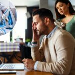 Um homem estressado trabalha em um laptop em casa enquanto sua esposa discute com ele, segurando o bebê.