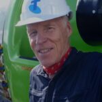 Um homem vestindo um traje de mergulho grosso segura um pedaço de gelo no oceano.