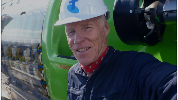 Este explorador canadense mergulhou sob o Pólo Norte, descobriu naufrágios Um homem vestindo um traje de mergulho grosso segura um pedaço de gelo no oceano.