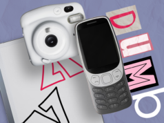 Estou procurando ativamente por tecnologia idiota em 2026 (e você também deveria) Ilustração de uma mão segurando um telefone básico em um fundo rosa e vermelho com a palavra 'DUMB' exibida ao lado.