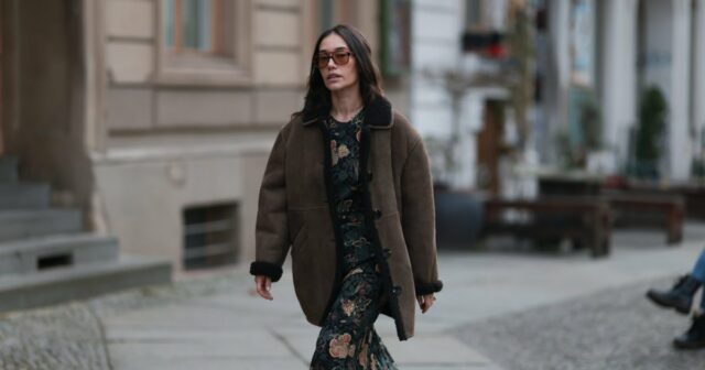 Diane Batoukina usa óculos escuros grandes quadrados marrom escuro da Dior, um pulôver de lã trançada rosa claro da Ralph Lauren, calça jeans azul desbotada / botões de cintura alta / pernas largas, uma bolsa branca latte de couro fosco 30 Montaigne da Dior, camurça branca e tênis de couro da Chanel, durante uma sessão de fotos de moda de estilo de rua, em 21 de abril de 2023 em Paris, França.