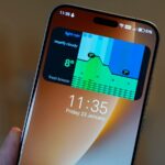 Uma mulher verificando seu telefone cercada por widgets meteorológicos flutuantes que exibem avisos de temperatura e qualidade do ar em um fundo vermelho.