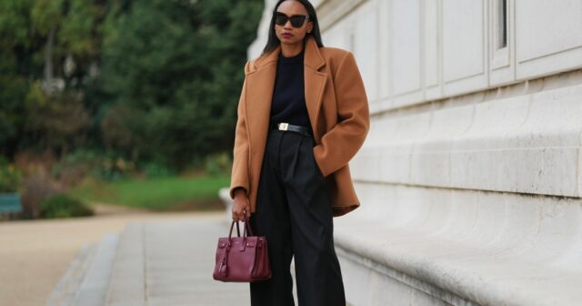 PARIS, FRANÇA - 31 DE DEZEMBRO: Yuwei Zhangzou usa cabelo preso em um rabo de cavalo trançado baixo, maquiagem com tez uniforme, sobrancelhas definidas e batom, fones de ouvido de arame, óculos de sol prateados ovais com lentes escuras da Celine, uma jaqueta de couro bomber marrom grande com gola alta e fecho de correr frontal, calça esportiva marrom de perna reta da Alo, uma pequena bolsa estruturada de shearling bege e marrom fofa com alça superior da Loro Piana, branca sapatos forrados de shearling com painéis de camurça marrom, cadarços contrastantes e sola plana de borracha da Moon Boot, segura um telefone celular, durante uma sessão de fotos de moda de rua, em 31 de dezembro de 2025 em Paris, França. (Foto de Edward Berthelot/Getty Images)