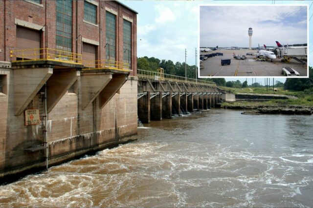 A torre de controle de tráfego aéreo do Aeroporto Internacional Hartsfield-Jackson Atlanta é vista do terminal, com vários aviões estacionados na pista.