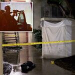 Vista do corredor de um complexo de apartamentos à noite, com fita amarela da cena do crime isolando uma área próxima a uma escada de metal e uma lona branca cobrindo uma seção do edifício.