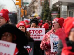 Hospital de Nova York alerta enfermeiras em greve que perderão benefícios de saúde à medida que a paralisação do trabalho se arrasta Enfermeiras impressionantes com chapéus vermelhos e casacos de inverno, uma delas com uma placa dizendo