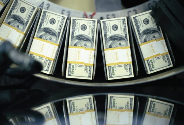 Bundles of freshly printed $100 bills roll through a conveyor belt at the United States Department of Treasury.