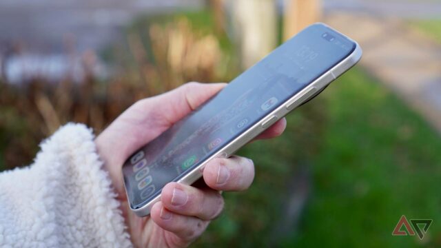 Uma mulher sorridente está sentada com um smartphone na mão, ao lado de um grande telefone exibindo o ícone do aplicativo Reddit, enquanto o mascote do Android e o personagem Snoo do Reddit aparecem de forma divertida.