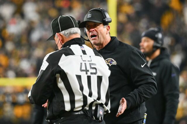 O técnico do Baltimore Ravens, John Harbaugh, conversa com um oficial.