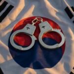Um par de algemas em uma bandeira sul-coreana. Juiz permite que réu do caso Hafa Adai Bingo viaje para a Coreia do Sul