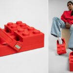 Uma pessoa vestindo Crocs vermelhos com tema Lego, jeans claros e um moletom vermelho, sentada em um bloco de madeira.