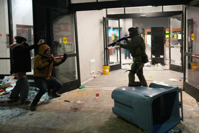 Manifestante segura cartazes durante um protesto em frente ao gabinete da senadora Amy Klobuchar, D-Minn., na segunda-feira, 26 de janeiro de 2026, em Minneapolis, depois que Alex Pretti foi morto a tiros por um oficial da Patrulha de Fronteira dos EUA no fim de semana. (Foto AP / Adam Gray)