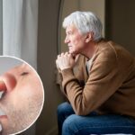 Um jovem com cabelo curto e barba por fazer cutuca o nariz.