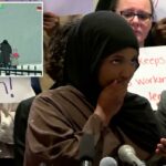 Uma mulher cobre a boca enquanto lê o telefone em uma coletiva de imprensa enquanto outra mulher fica atrás de um microfone à sua direita.