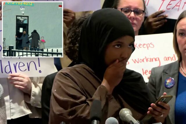 Uma mulher cobre a boca enquanto lê o telefone em uma coletiva de imprensa enquanto outra mulher fica atrás de um microfone à sua direita.