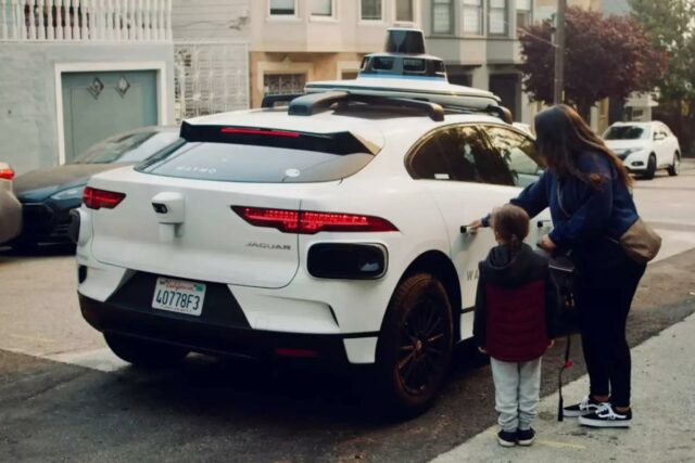 Mãe e filho entrando em um carro autônomo da Waymo.
