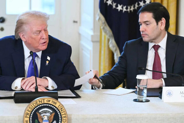 SAUL LOEB / AFP via Getty O presidente Donald Trump dá um tapinha nas costas do secretário de Estado Marco depois de ler em voz alta uma nota privada de Rubio durante uma entrevista coletiva em 9 de janeiro de 2026