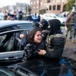 Agentes do ICE detêm uma mulher enquanto a retiram de um carro em Minneapolis.