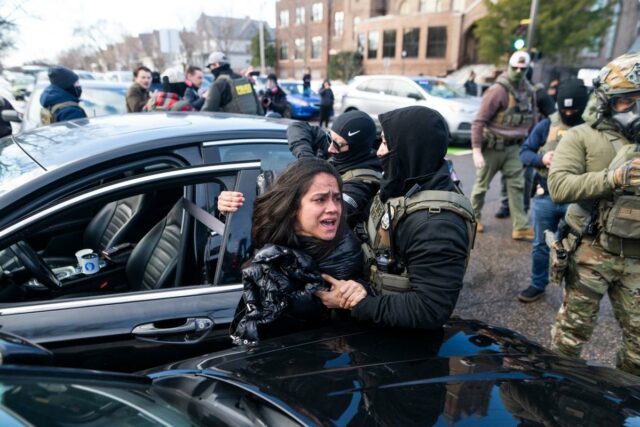 Agentes do ICE detêm uma mulher enquanto a retiram de um carro em Minneapolis.