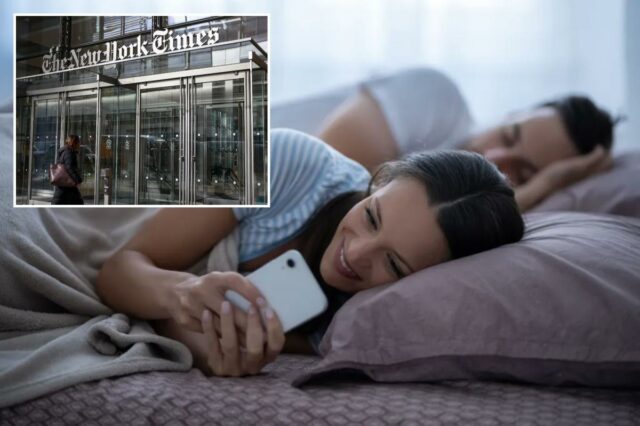 Uma mulher verifica o telefone na cama enquanto seu parceiro dorme ao lado dela.