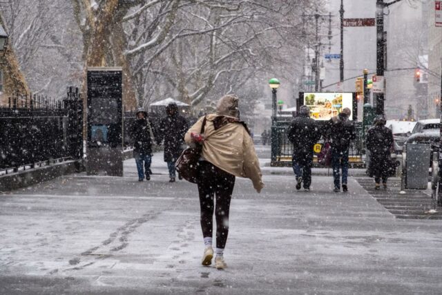 Pessoas caminhando na neve e na chuva gelada na Broadway, perto do City Hall Park, em Nova York.