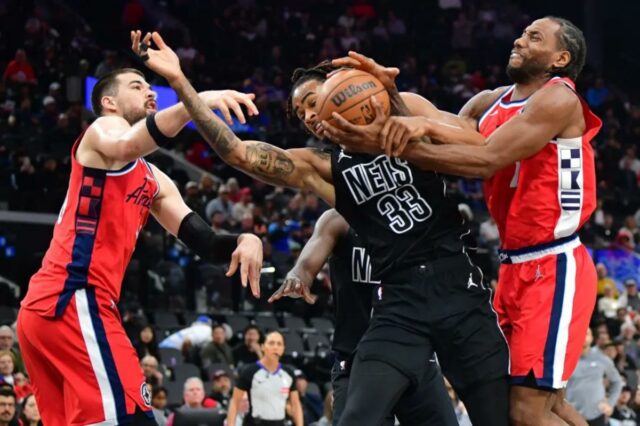 O pivô do Los Angeles Clippers, Brook Lopez (11), e o atacante Kawhi Leonard (2) jogam pela bola contra o pivô do Brooklyn Nets, Nic Claxton (33), durante o primeiro tempo no Intuit Dome. 