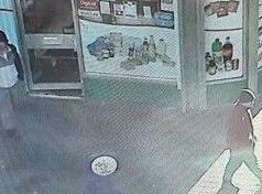 Nova CCTV divulgada em busca de assassino foragido A imagem do CCTV mostra dois homens passando por uma pequena loja. Um homem usa chapéu preto, casaco preto, calça cinza e camisa pólo. Outro usa o que parece ser uma jaqueta vermelha e um chapéu escuro.