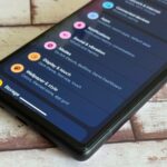 Um homem em um pufe navegando em seu telefone com notificações aparecendo acima dele.