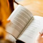 Page Match do Spotify pode sincronizar audiolivros com versões em papel | A foto mostra o close de uma mulher lendo um livro em um café