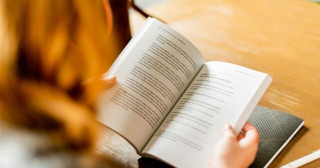 Page Match do Spotify pode sincronizar audiolivros com versões em papel | A foto mostra o close de uma mulher lendo um livro em um café