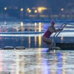 Um membro do Serpentine Swimming Club dá um mergulho matinal no Hyde Park hoje