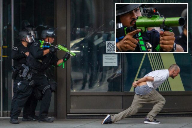 Um policial de Los Angeles aponta sua arma de bala de borracha para uma multidão durante um protesto.