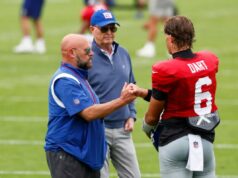 O que Brian Daboll está dizendo aos treinadores sobre a estreia dos Giants, Jaxson Dart O técnico do Giants, Brian Daboll, dá um soco no quarterback Jaxson Dart, com o proprietário John Mara atrás deles, em um campo de futebol.