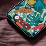 spotify na tela de um celular que está mexendo em uma xícara de café