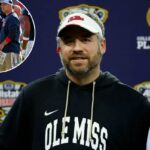 O técnico do Ole Miss Rebels, Pete Golding, sorrindo enquanto usava viseira e moletom durante o Sugar Bowl.
