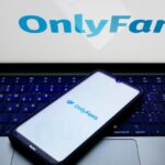 The OnlyFans logo is being displayed on a smartphone screen and on a computer screen