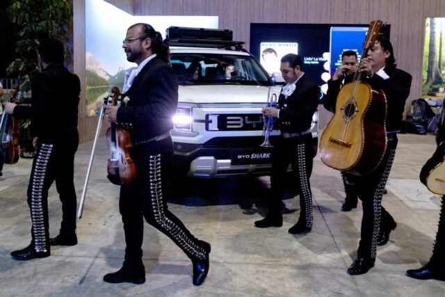 Membros da banda Mariachi em frente a uma caminhonete branca BYD Shark.