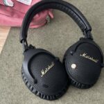 fones de ouvido Marshall em um tapete de mesa verde encostado em uma bolsa rosa