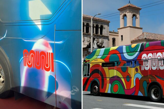 Um ônibus SF MUNI 5 Fulton envolto em cores tie-dye passa por um prédio.