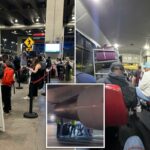 Tripulantes de terra em um campo de aviação à noite, com um motor de avião visível acima deles.